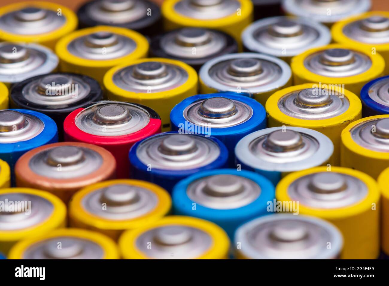 Many used AA electric batteries, lined up upright and viewed from above. Concepts of energy