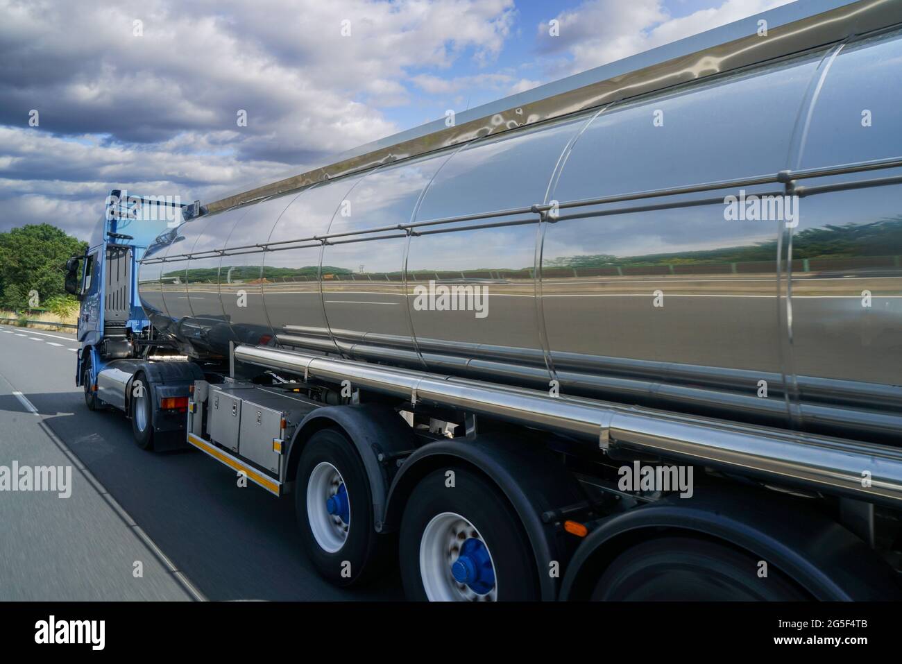 A tank truck with a shiny, reflective silver gas barrel driving on an ...
