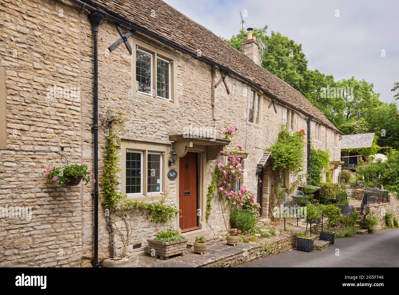 Front door and pink roses at a cottage in Castle Combe, a picturesque village in the Cotswolds Area of Natural Beauty in Wiltshire, south-west England Stock Photo