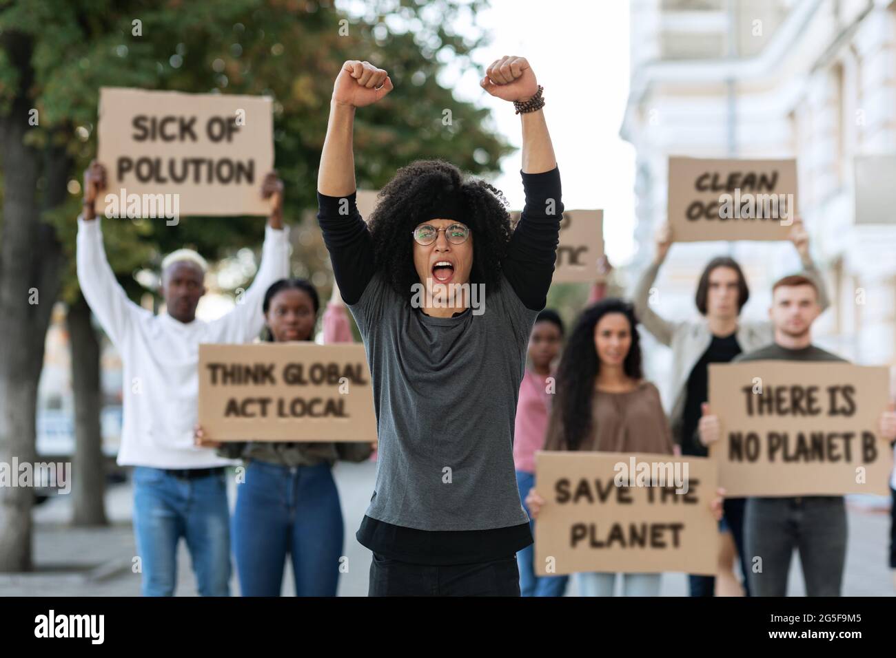 Black guy leader leading international group protestors, raising fists up, millennial people of nationalities holding placards and chanti Stock Photo - Alamy