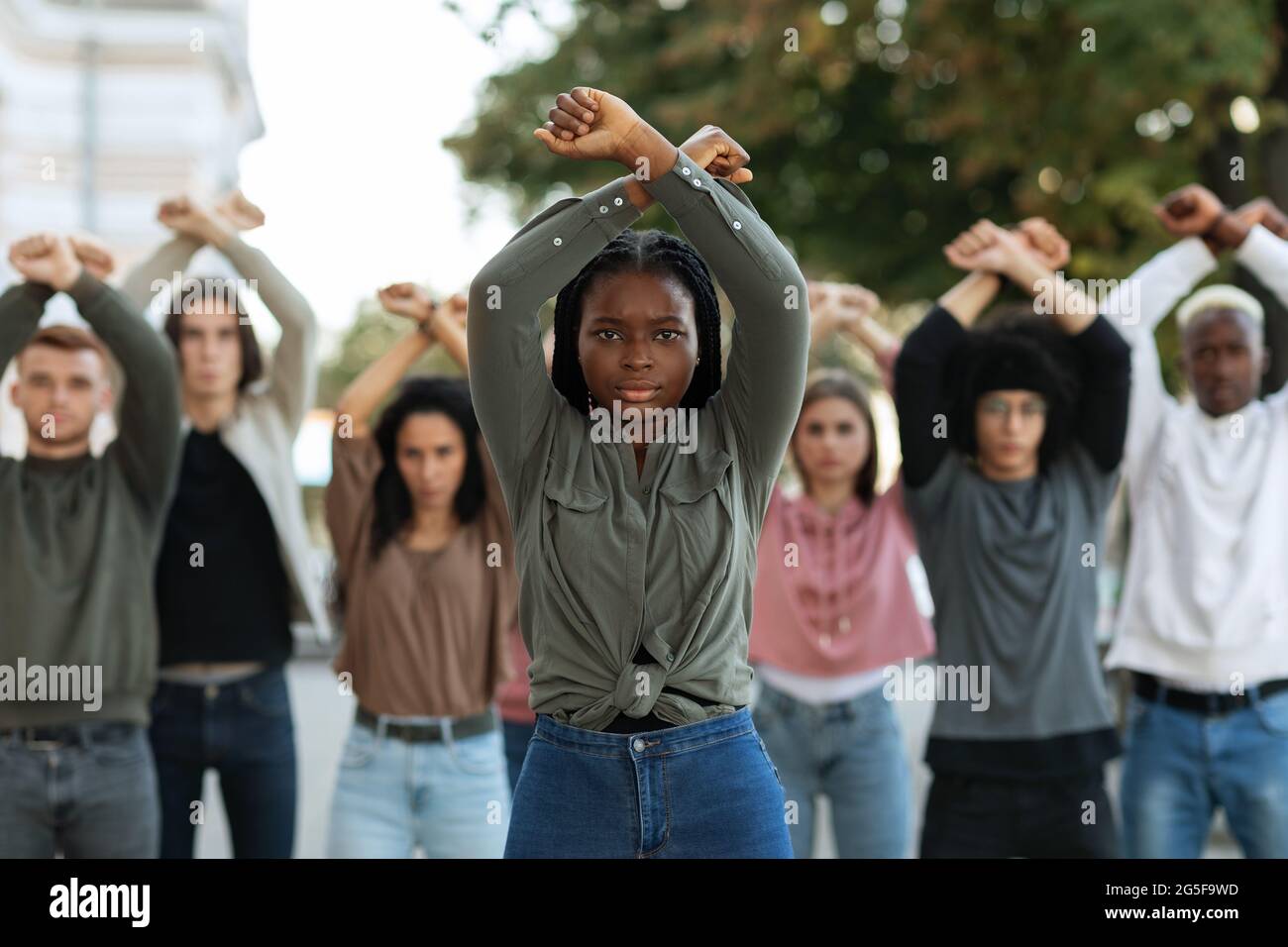 Black lady guiding multiracial group of activists, rasising fists up ...