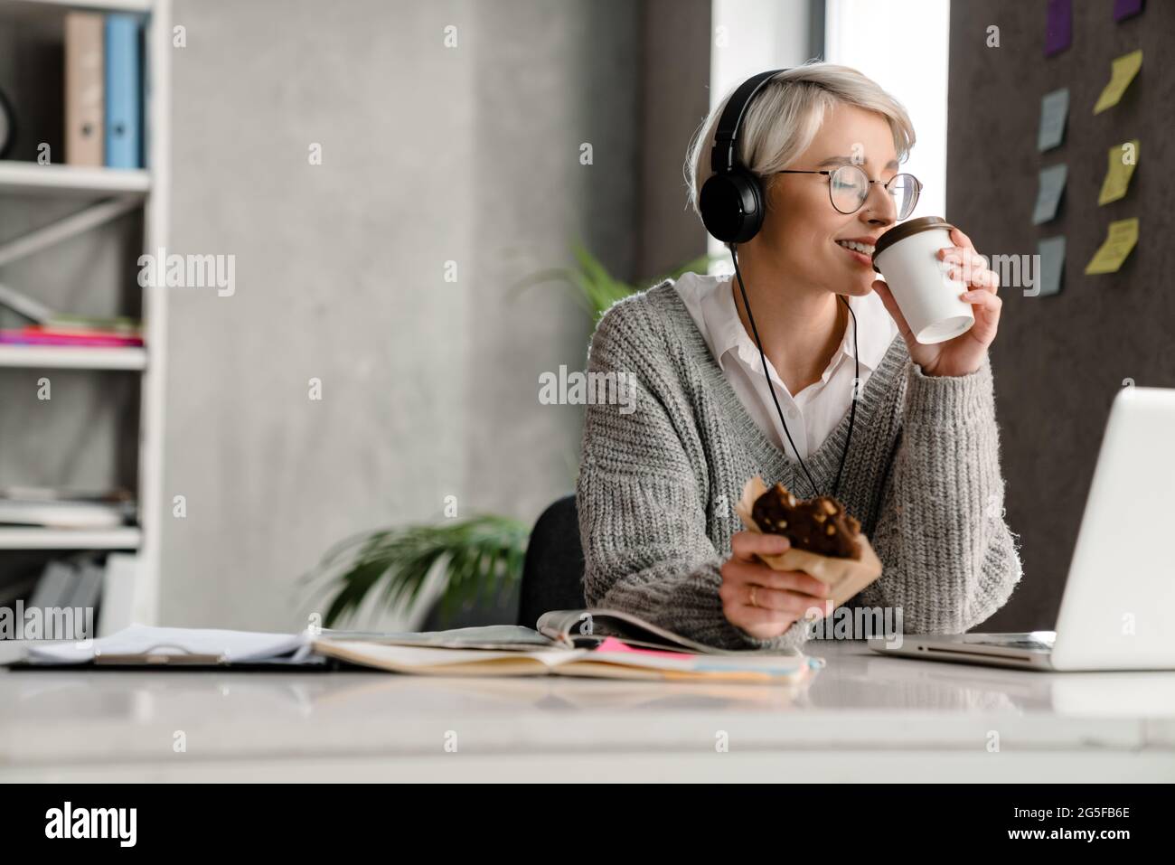 Happy mid aged woman in headphones on a video call via laptop computer ...