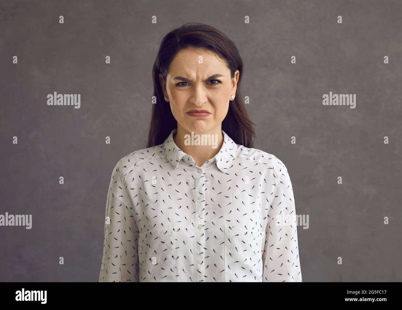Portrait of an emotional young woman with a frowning grimace who expresses her disgust and dislike. Stock Photo