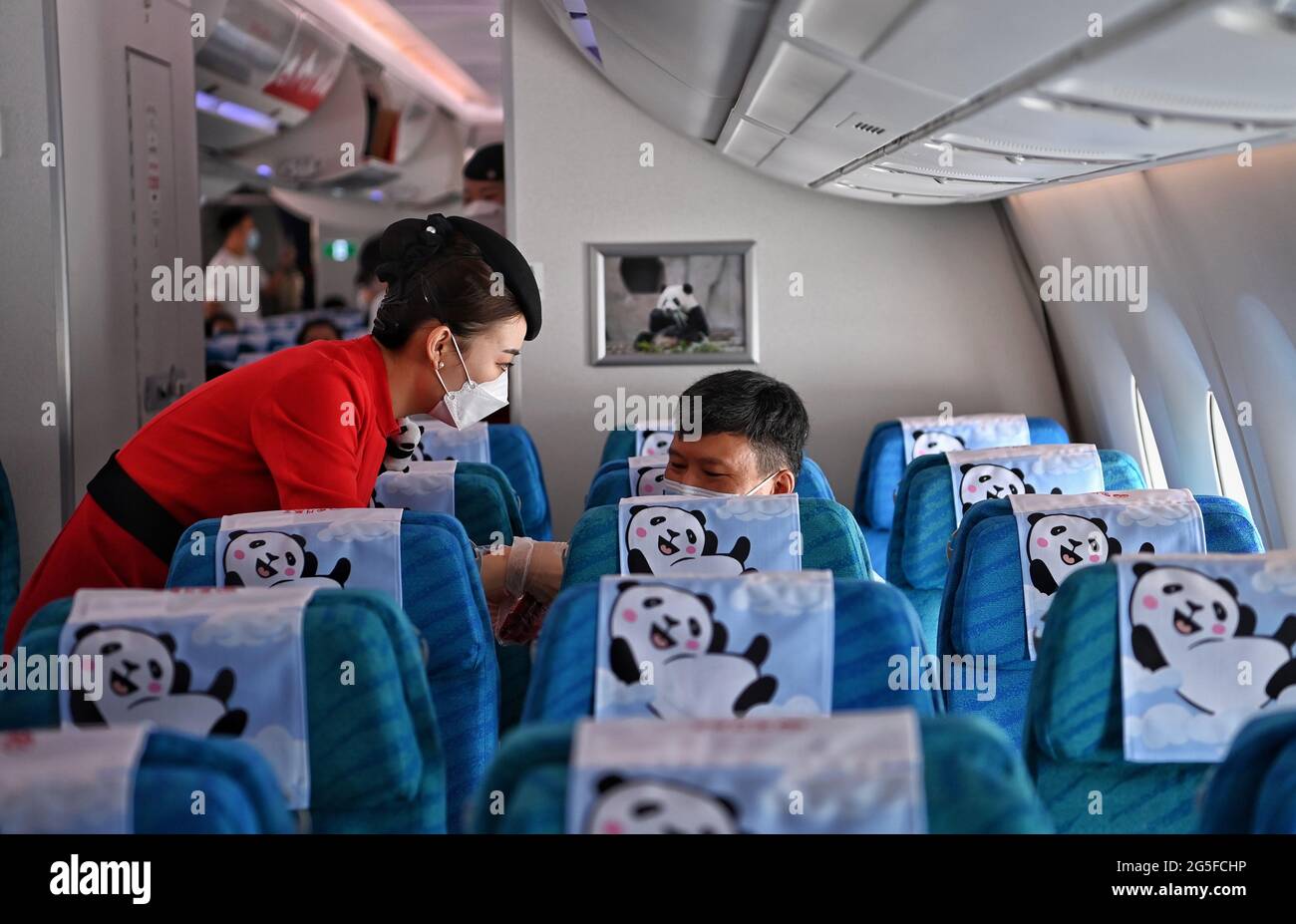 Chengdu. 27th June, 2021. A cabin crew member explains safety guidelines to a passenger on flight 3U8001 of Sichuan Airlines at Chengdu Tianfu International Airport in southwest China's Sichuan Province, June 27, 2021. Chengdu Tianfu International Airport in southwest China's Sichuan Province has opened for operations, with a Sichuan Airlines flight bound for Beijing taking off on Sunday morning. Credit: Wang Xi/Xinhua/Alamy Live News Stock Photo
