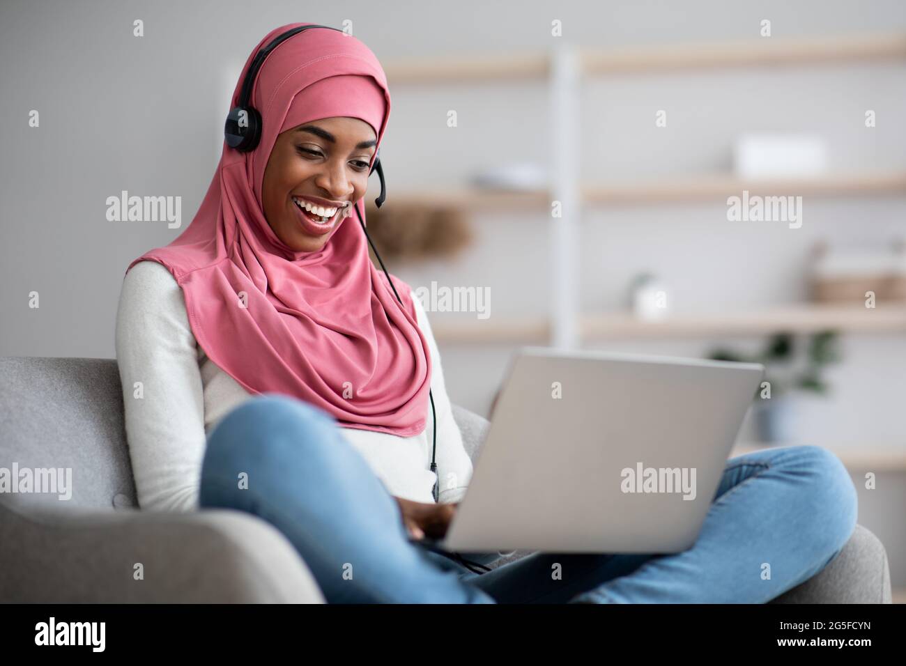 Cheerful Black Muslim Lady In Hijab And Headset Watching Webinar On ...