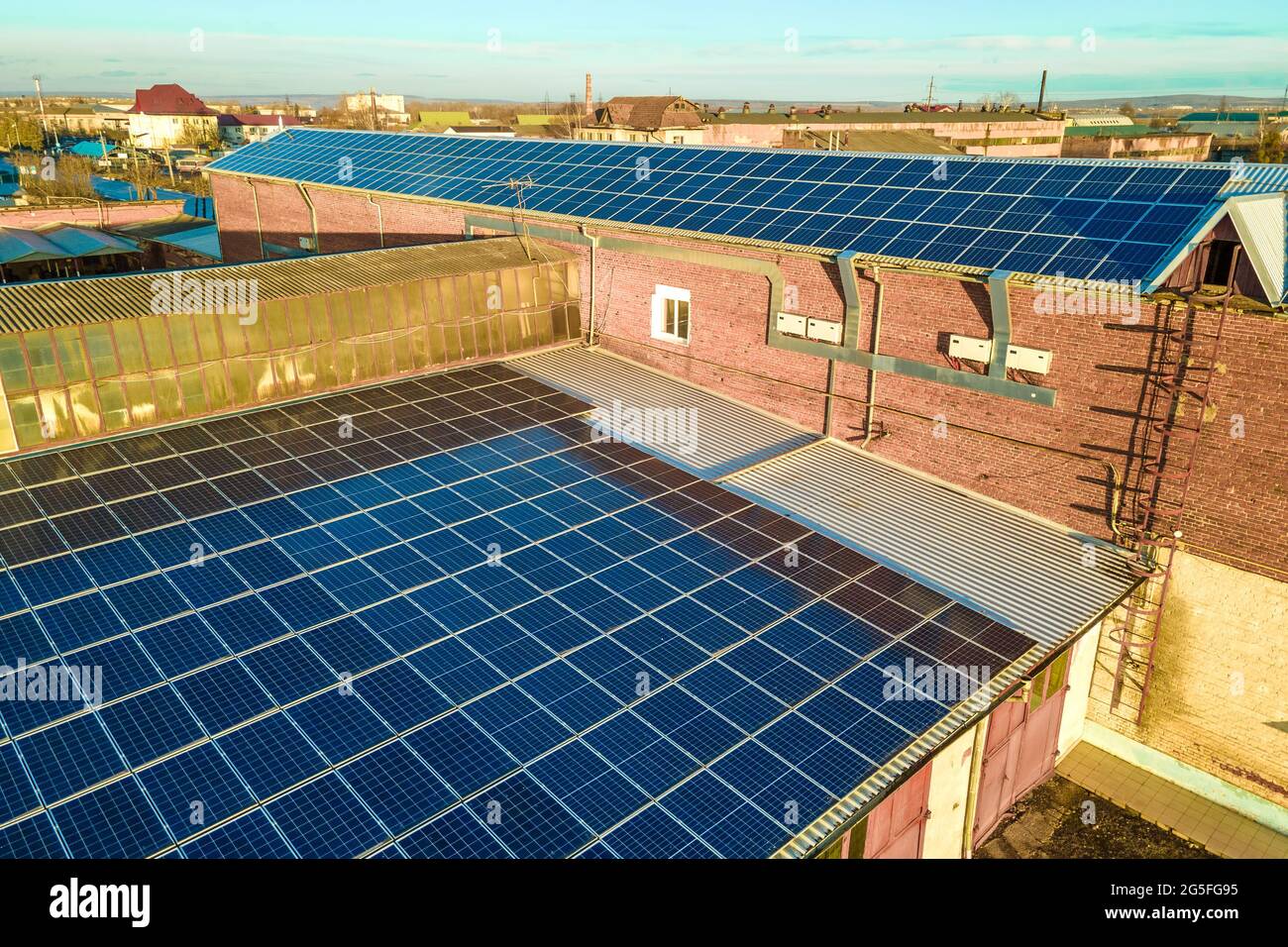 Blue photovoltaic solar panels mounted on industrial building roof for ...