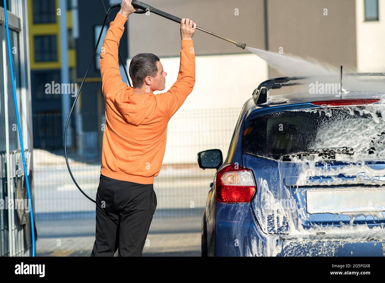 Young driver man washing his car with contactless high pressure water