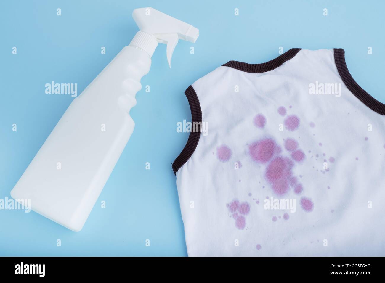 Juice stain with stain remover spray for clothes. Isolated on a blue