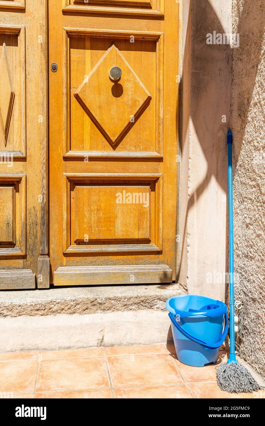 Wooden doors, blue bucket and mop. Calvi, Corsica, France Stock Photo