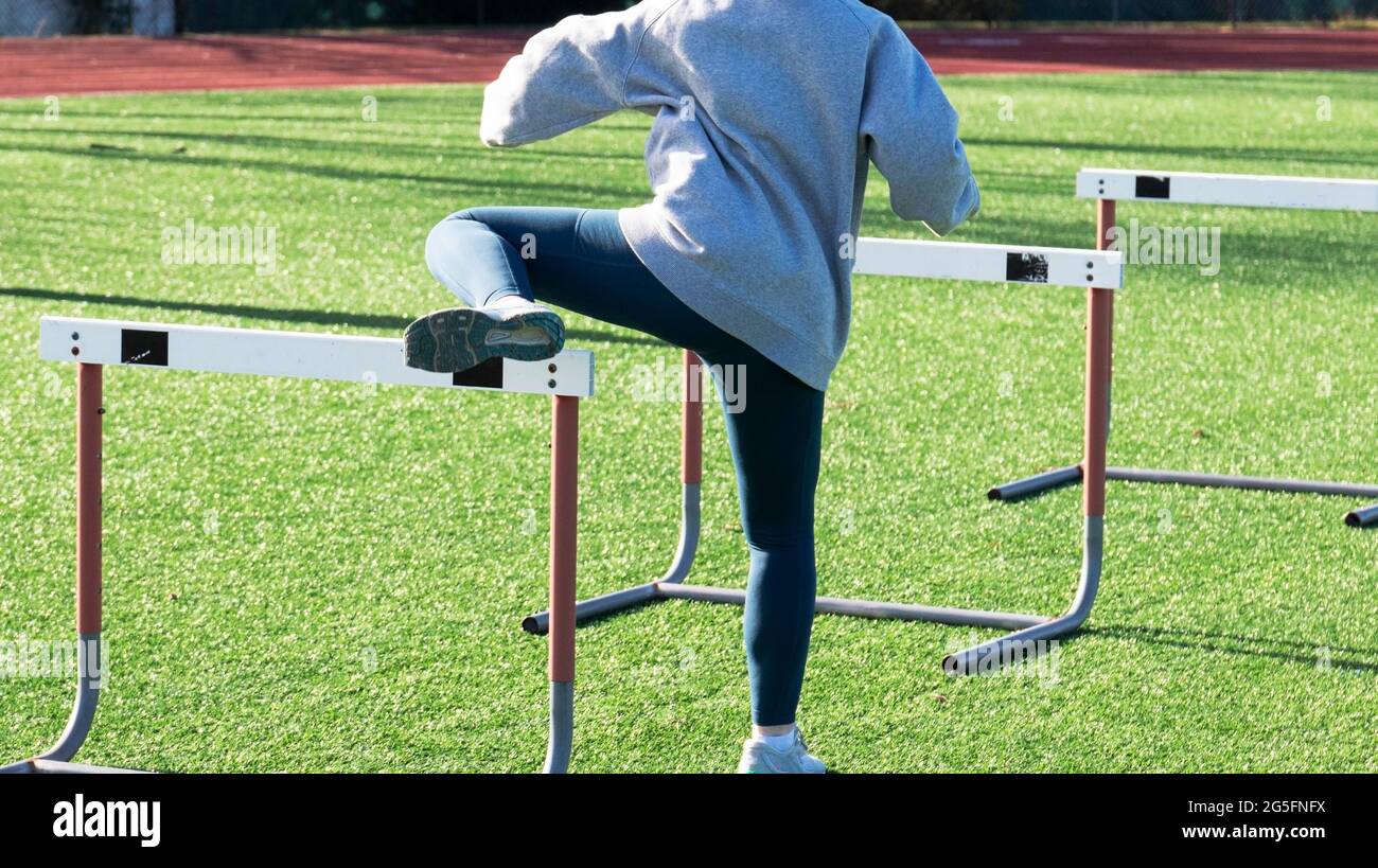 Rear View of a high school track runner performing hurdle trail leg