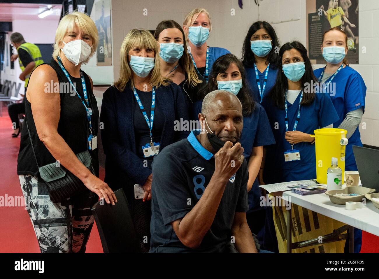 Watford, UK.  27 June 2021. Former Watford player Luther Blissett poses with medical staff at a pop-up mass vaccination clinic at Watford FC’s Vicarage Road Stadium as part of the “Grab a jab” campaign. The NHS is also promoting a number of walk-in clinics this weekend across the capital to try to increase the number of over 18s receiving a jab as cases of the Delta variant are reported to be on the rise.  Credit: Stephen Chung / Alamy Live News Stock Photo