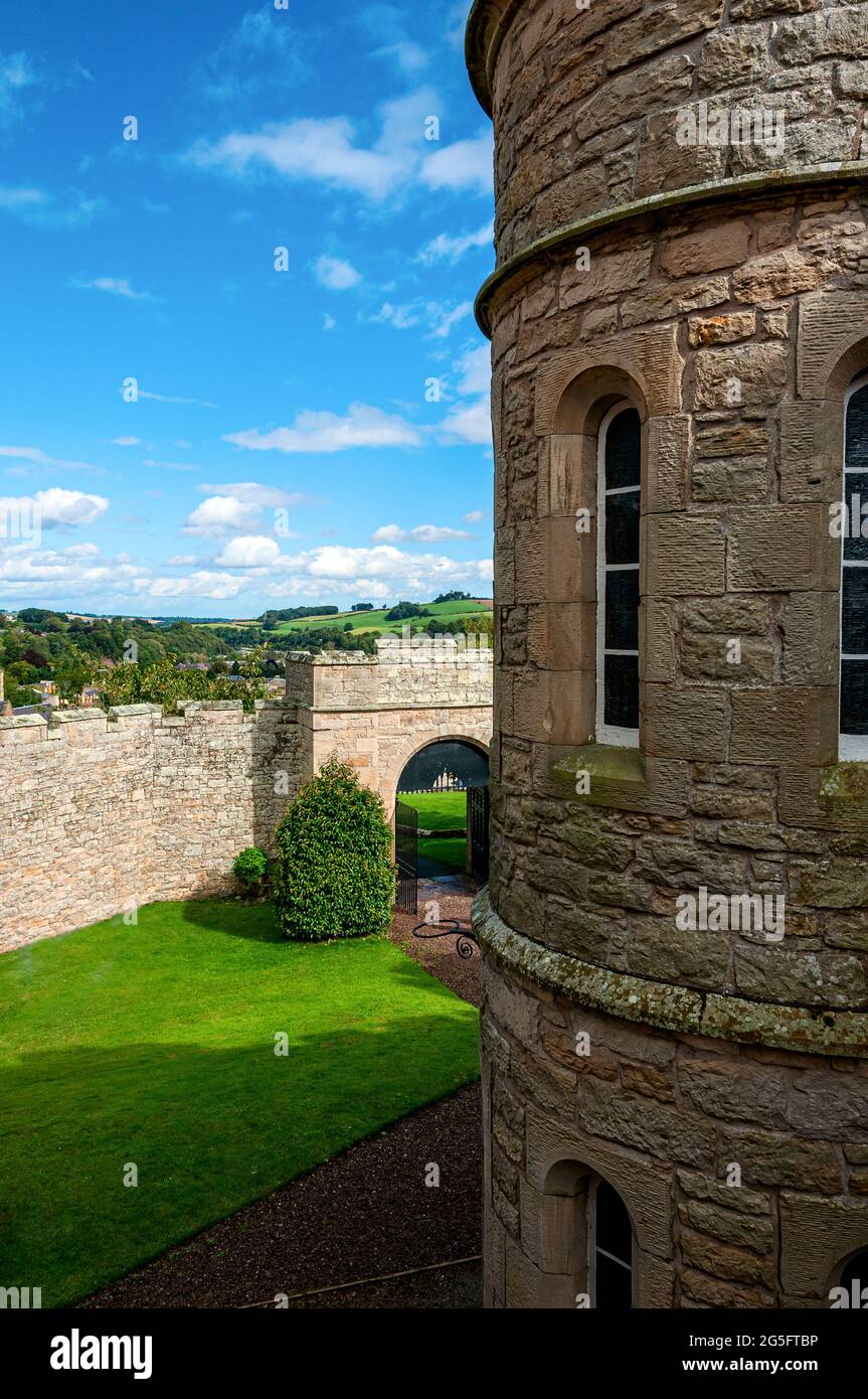 A tower of the Gaoler's House at Jedburgh Prison looks out upon a lawn in front of the retaining wall, the portcullis gate, and the countryside beyond Stock Photo