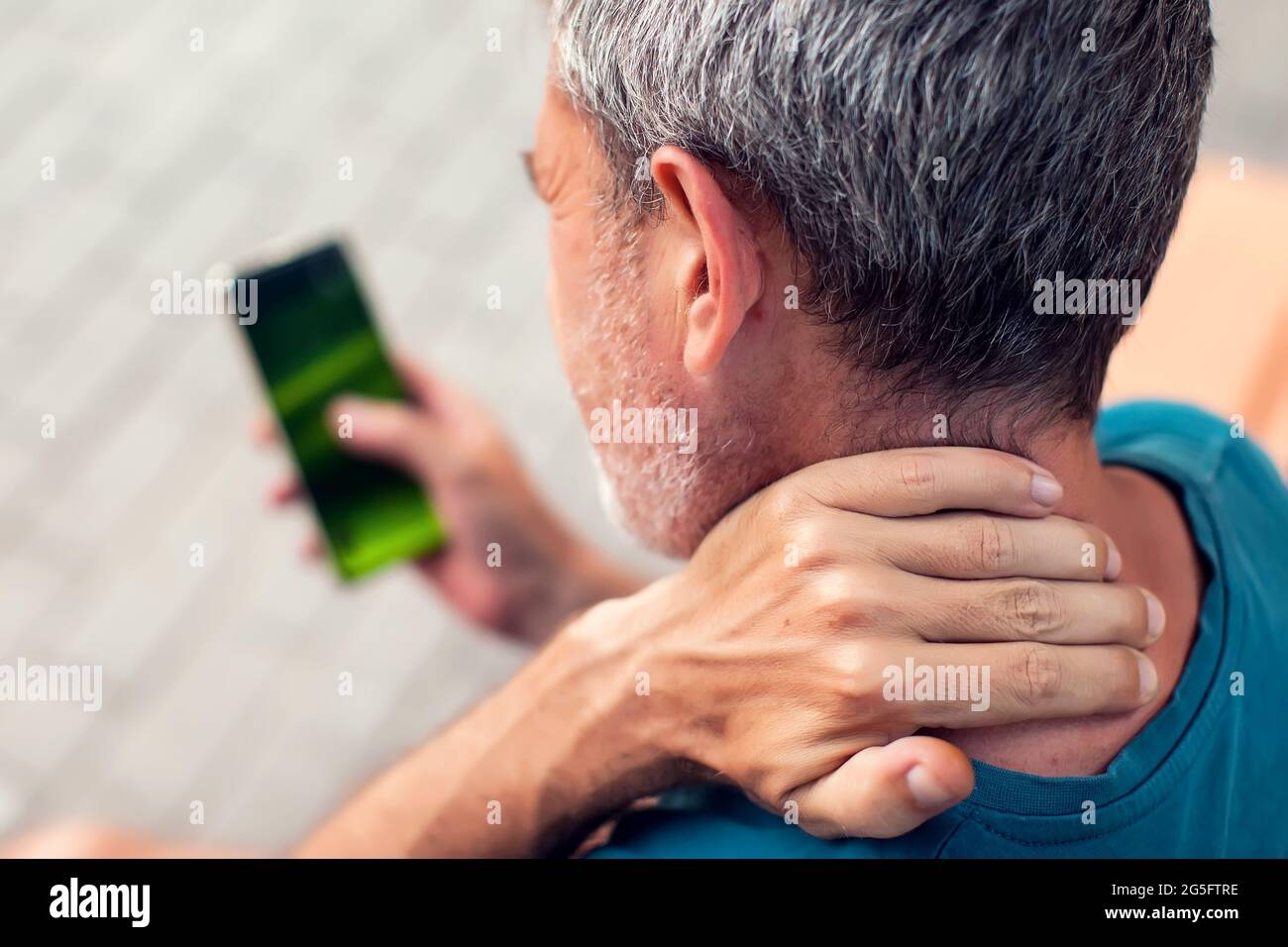 Neck pain using smartphone outdoor. Healthcare, lifestyle and technology concept Stock Photo