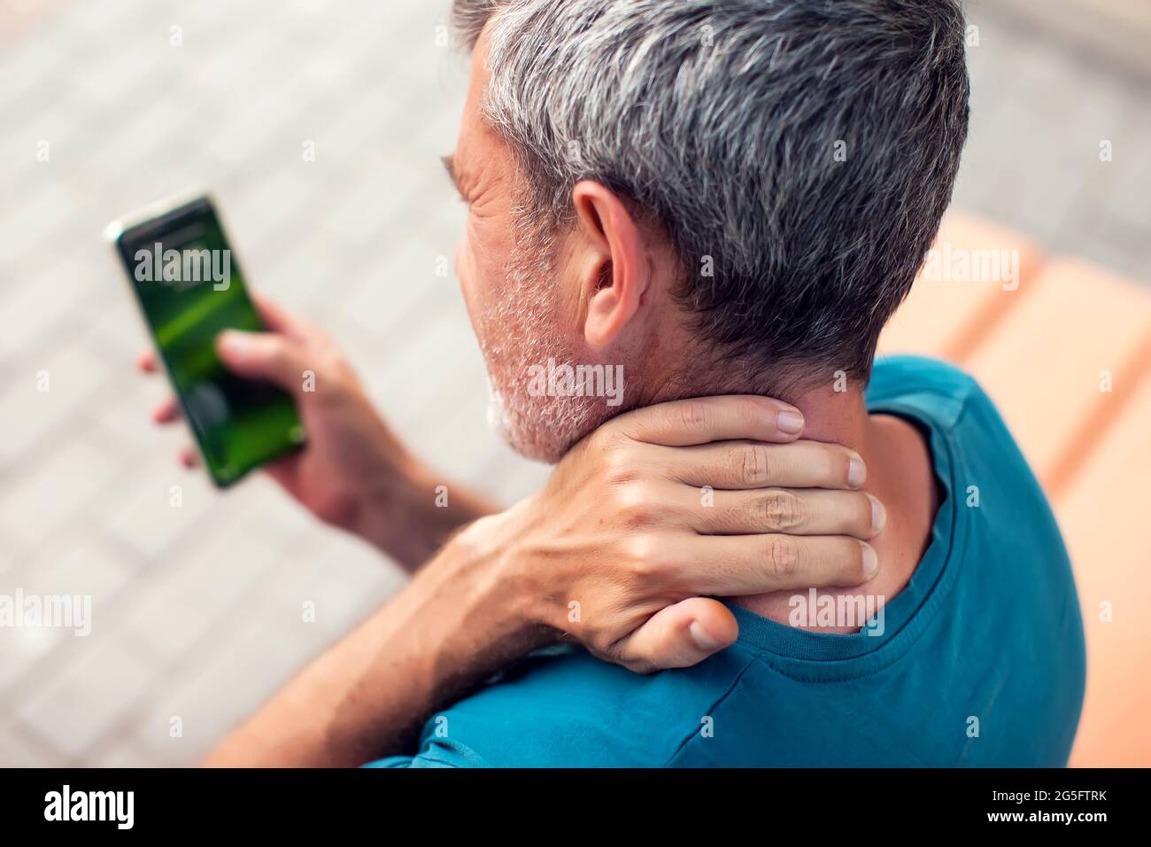 Neck pain using smartphone outdoor. Healthcare, lifestyle and technology concept Stock Photo