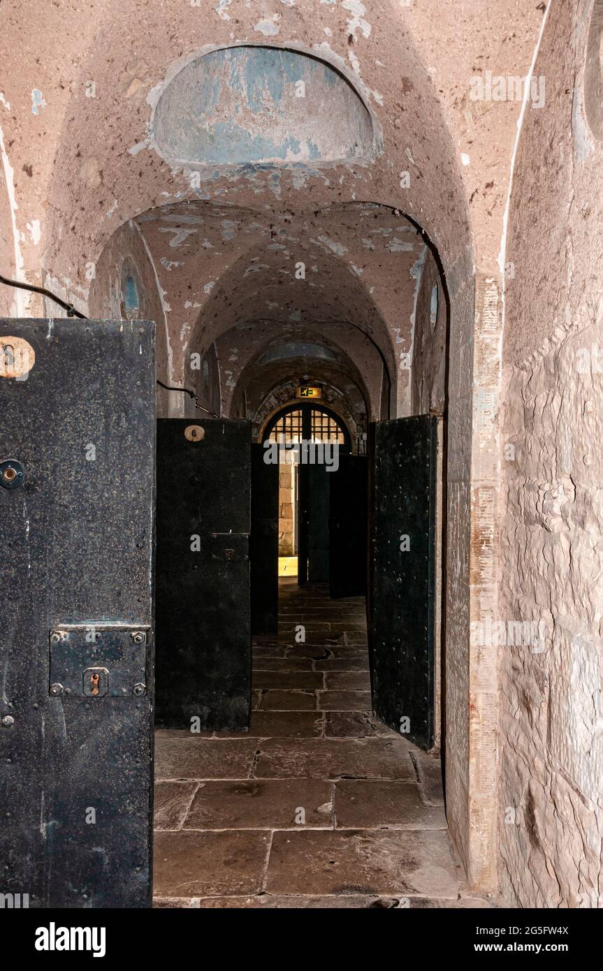 A corridor with arches in the ceiling and flagstones on the floor houses prison cells on either side as it traverse a cell block at Jedburgh old jail Stock Photo