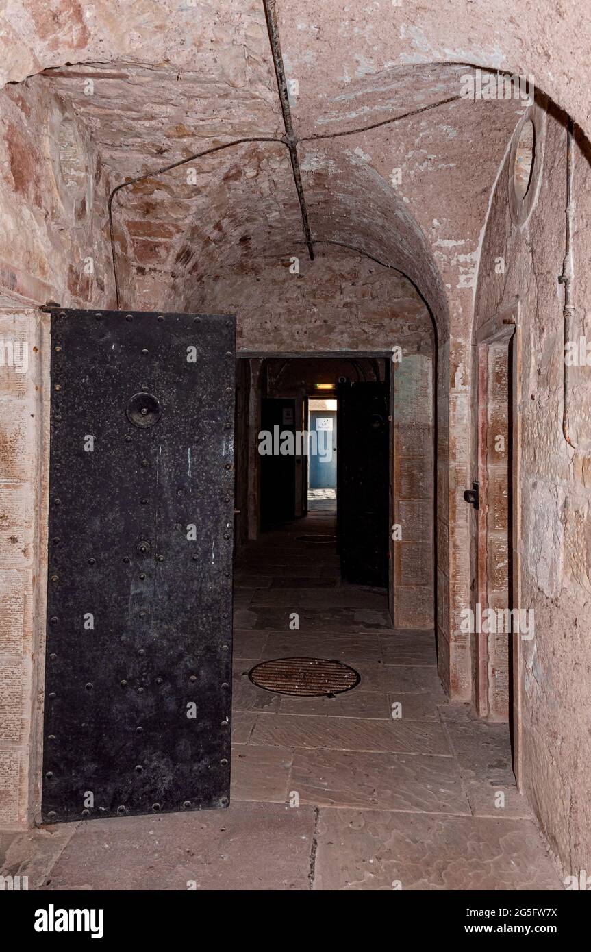 A corridor with arches in the ceiling and flagstones on the floor houses prison cells on either side as it traverse a cell block at Jedburgh old jail Stock Photo