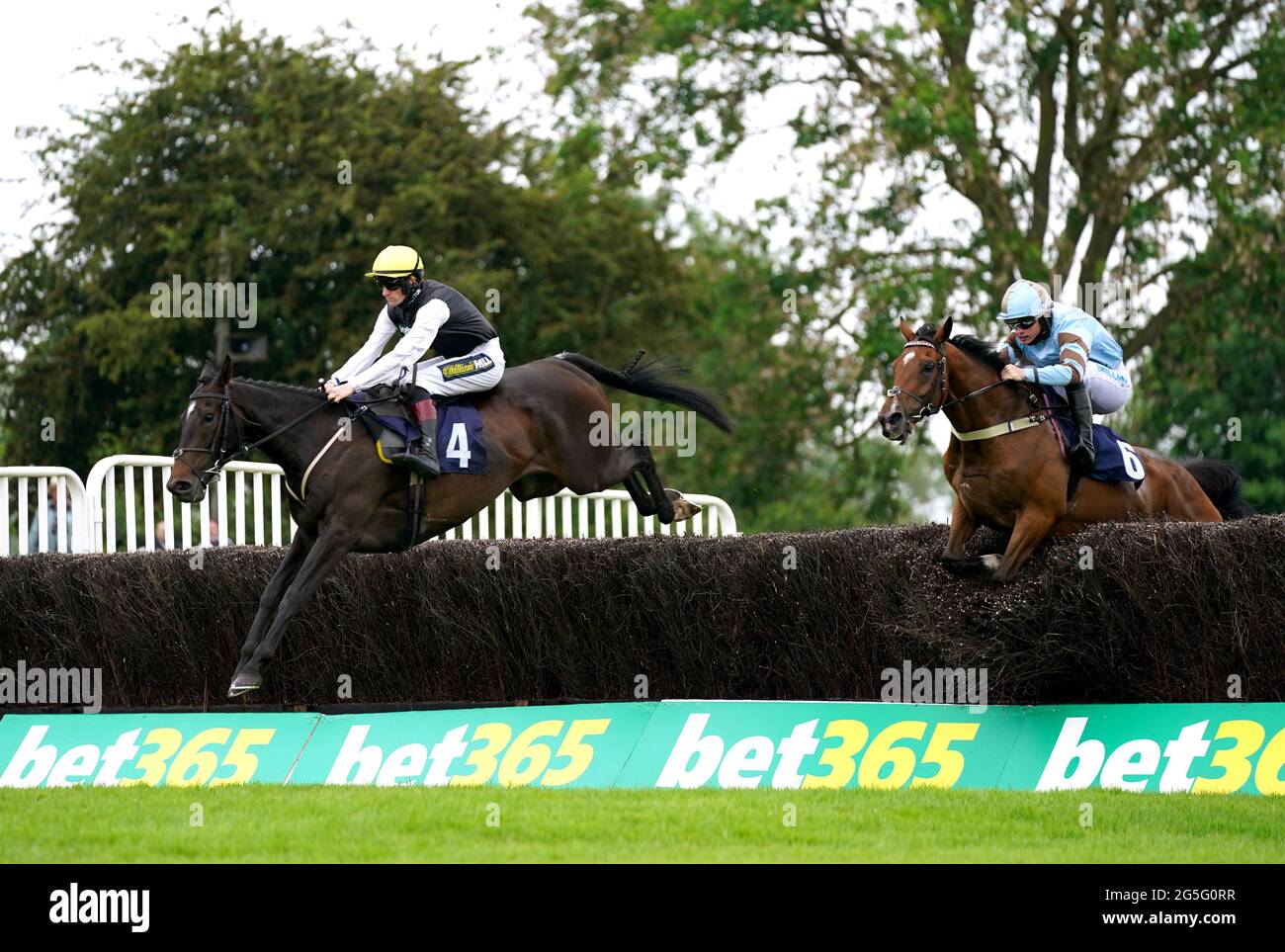 Goa Lil ridden by Sam Twiston-Davies (left) and Statuario ridden by James Bowen clear a hurdle whilst competing in the bet365 Handicap Chase at Uttoxeter Racecourse. Sunday June 27, 2021. Stock Photo