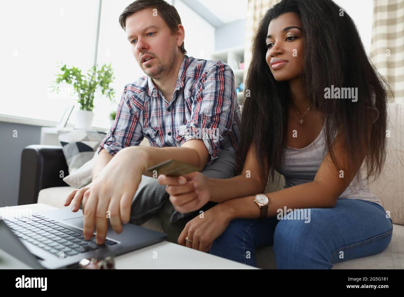 Caucasian man and african american woman sitting behind laptop screen ...