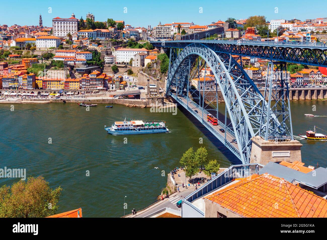 Porto, Porto District, Portugal. An excursion boat by the Dom Luis I bridge which crosses the Douro river and links Vila Nova de Gaia, bottom, and Por Stock Photo