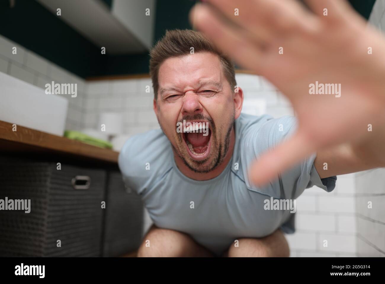 Man sitting on toilet and screaming in pain Stock Photo Alamy