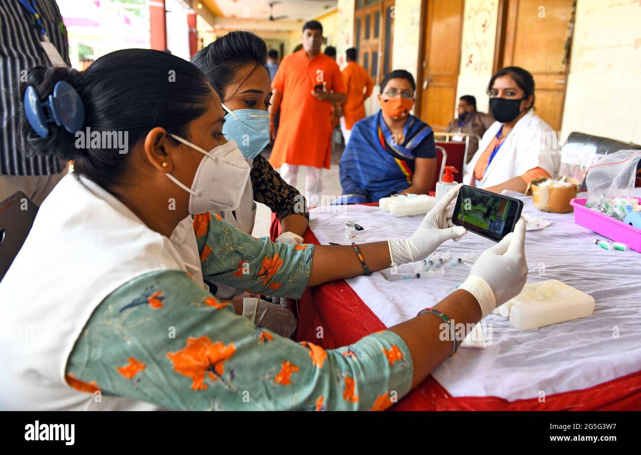 Beawar, India. 27th June, 2021. Health workers listen to Indian Prime Minister Narendra Modi's 'Mann ki Baat' while a medic administers a dose of COVID-19 vaccine to a beneficiary during a special one-day vaccination drive at a vaccination center in Beawar. PM Modi speaks about Indian participation in Olympics, vaccine hesitancy, rainwater harvesting and more. (Photo by Sumit Saraswat/Pacific Press) Credit: Pacific Press Media Production Corp./Alamy Live News Stock Photo