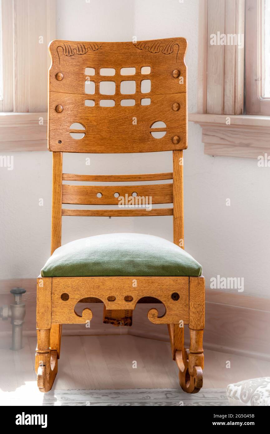 Antique rocking chair with fancy woodwork and carving siting int he corner of a room - Close-up.j Stock Photo
