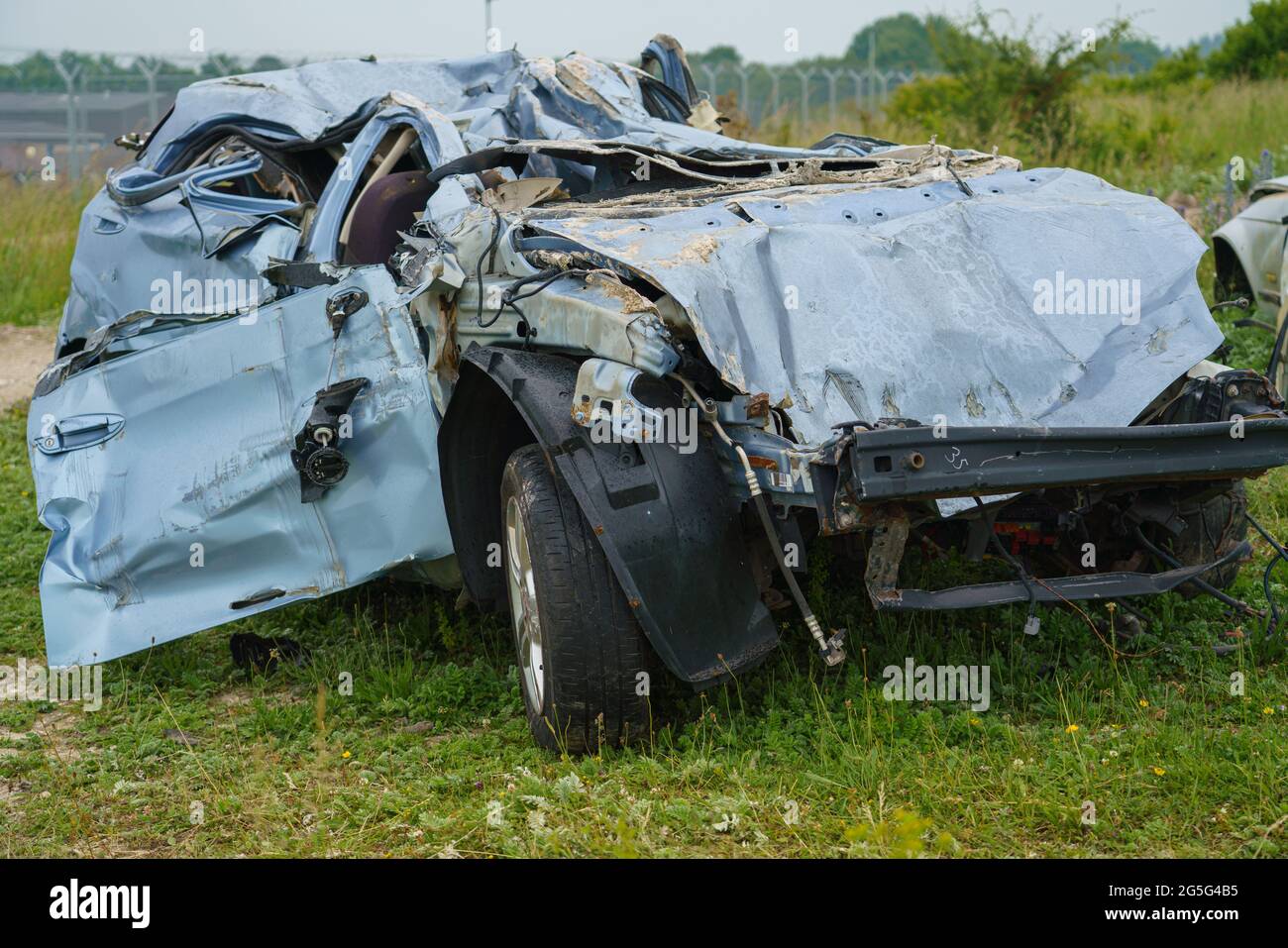 the crushed remains of a car after a an army tank has deliberately driven over it leaving just scrap metal Stock Photo