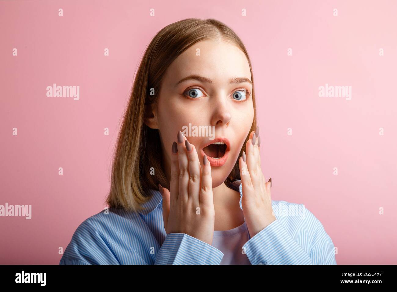 Emotional portrait of surprised business woman with open mouth. Close up portrait of teenage girl student in shirt over isolated color pink background Stock Photo