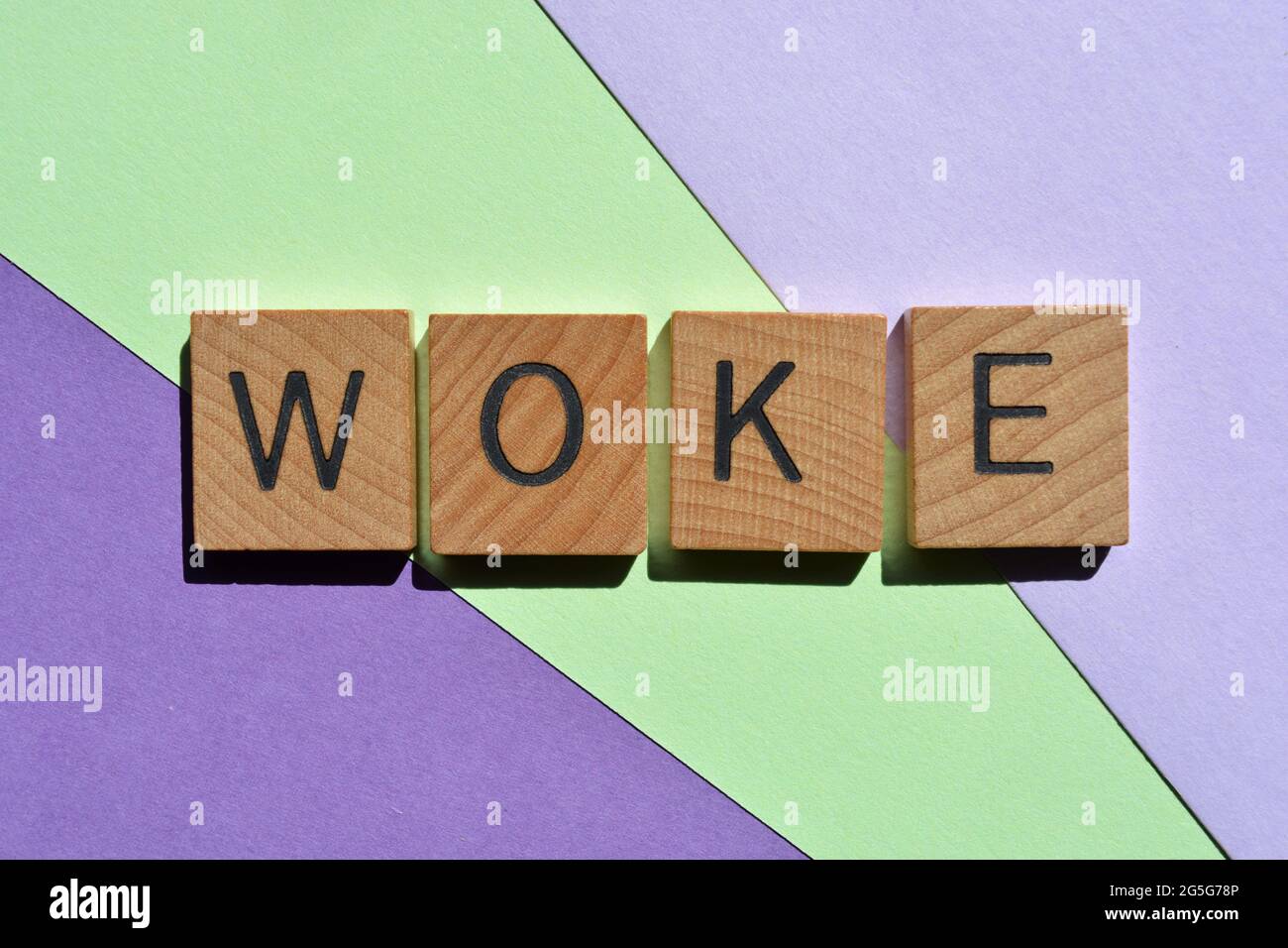 Woke, word in wooden alphabet letters isolated on green and purple background Stock Photo