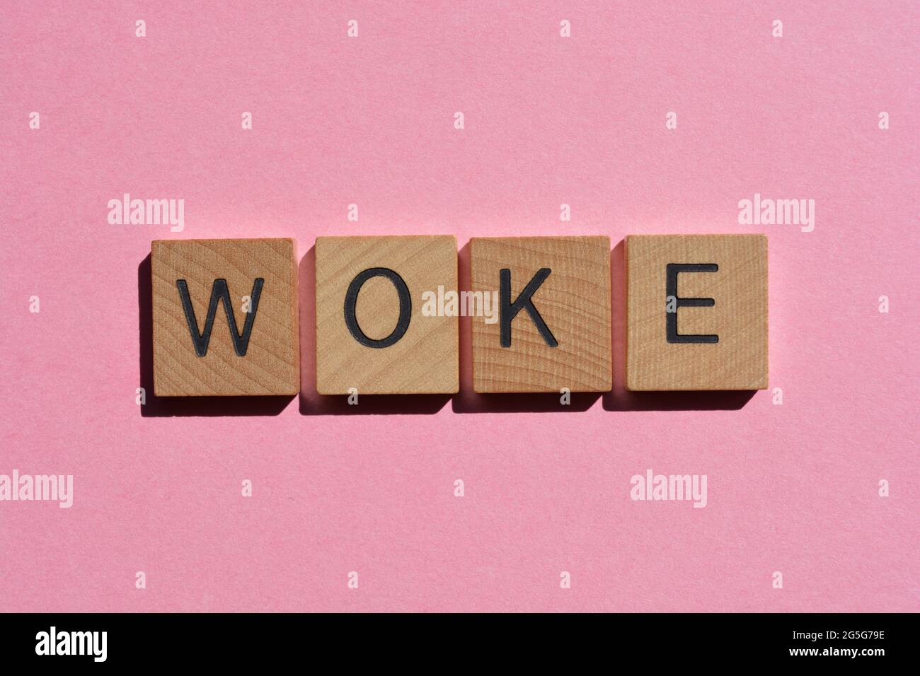 Woke, word in wooden alphabet letters isolated on pink Stock Photo
