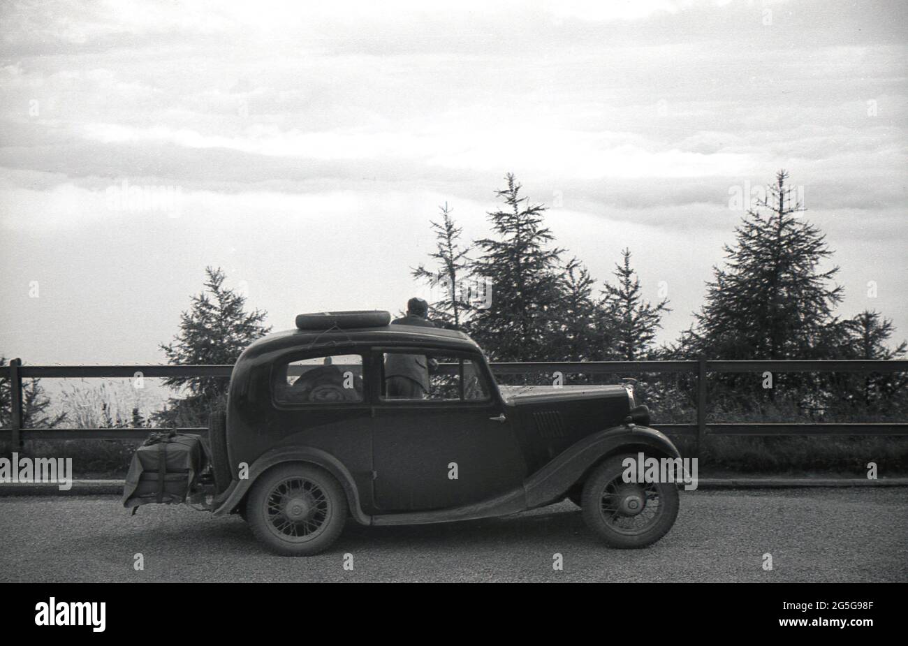 1934, historical, touring Bohemia, the western part of Czechoslavia pre-WW2. A young man standing by his car, a British Morris Eight looking over the surrounding landscape. This area of Czechoslovakia was known and referred to at this time as the Sudetenland, the historical name for the sudeten German people living in the western Czech lands of Bohemia and other border areas. Stock Photo