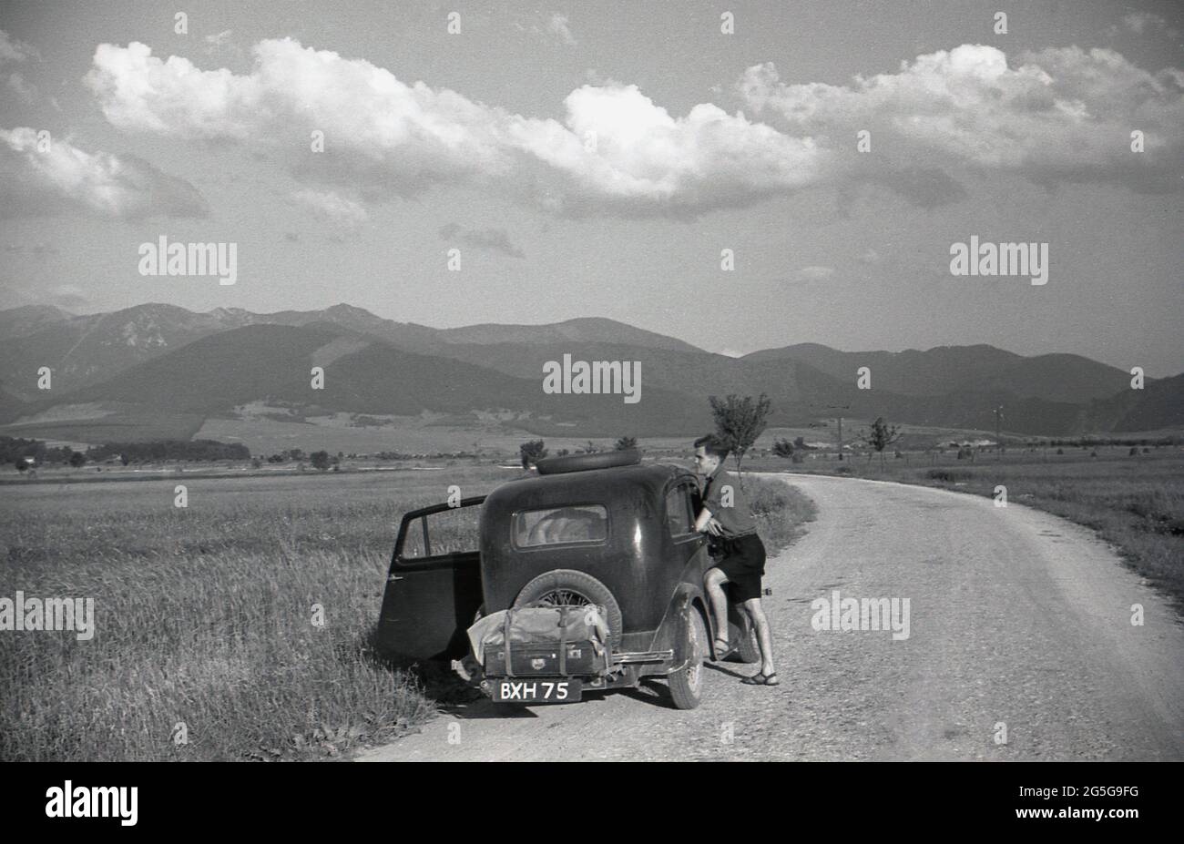 1930s, historical, touring Czechoslavia pre-ww2, a young man standing on a country road, by his British car, a Morris 8, looking over the surrounding landscape. After WW1 and the establishment of an independent Czechoslovakia state, several border areas of the country, including the historical western area of Bohemia, were now occupied by a majority of German speakers, known by the historical German name as the Sudentenland. 1938 saw the Sudeten crisis, the Munich Agreement and then WW2. Stock Photo