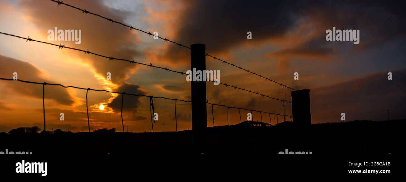 Time lapse sunset over barbed wire fence Stock Photo - Alamy