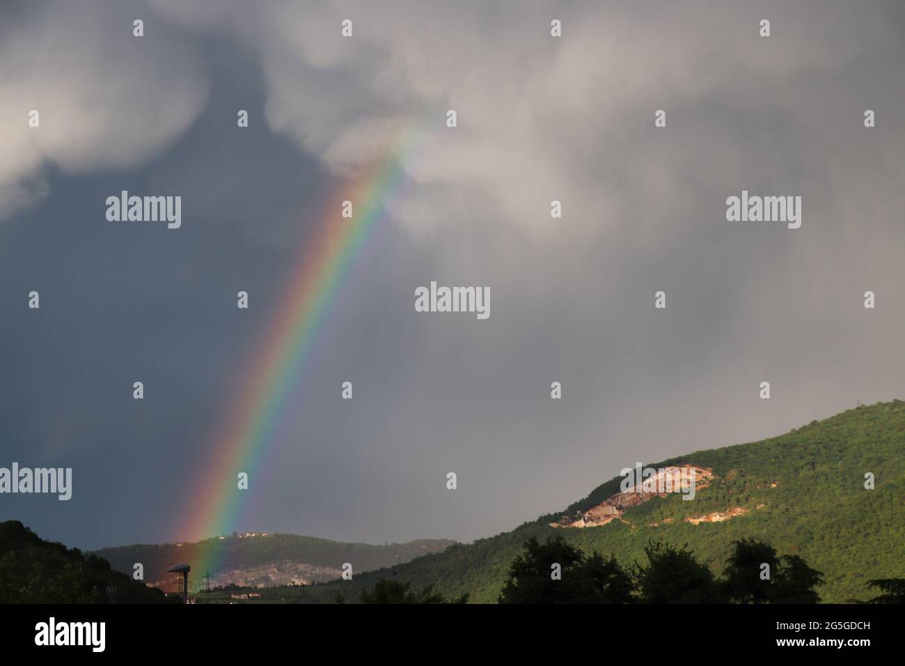 After the rain and a colorful Rainbow in the background of the countryside. Rainbow rural landscape Stock Photo