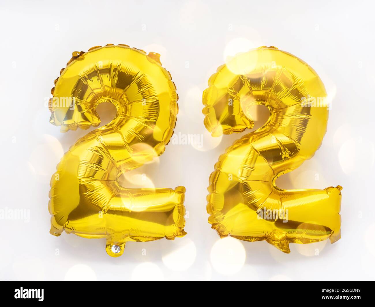 22 golden foil balloon numbers party decor on white background, birthday  concept with festive lights Stock Photo - Alamy