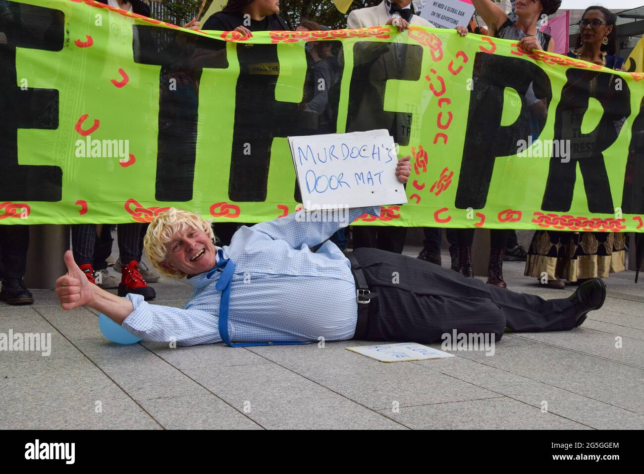 London, United Kingdom. 27th June 2021. A demonstrator dressed as Boris Johnson lies down outside News UK during the Free The Press protest. Extinction Rebellion demonstrators marched from Parliament Square to News UK headquarters, owned by Rupert Murdoch, in London Bridge, in protest of misinformation, corruption, and the inaccurate and insufficient coverage of the climate crisis by Murdoch's newspapers. (Credit: Vuk Valcic / Alamy Live News) Stock Photo