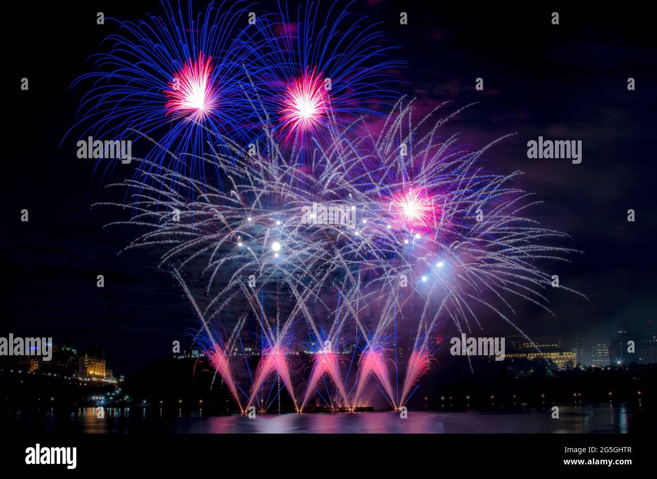 Creative firework display over water and the skyline at the International Sound of Light fireworks competition (Les Grands Feux du Casino Lac-Leamy) Stock Photo