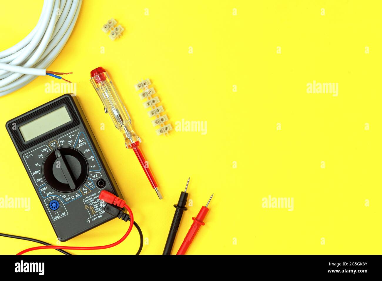 Digital multimeter and indicator screwdriver on a yellow background