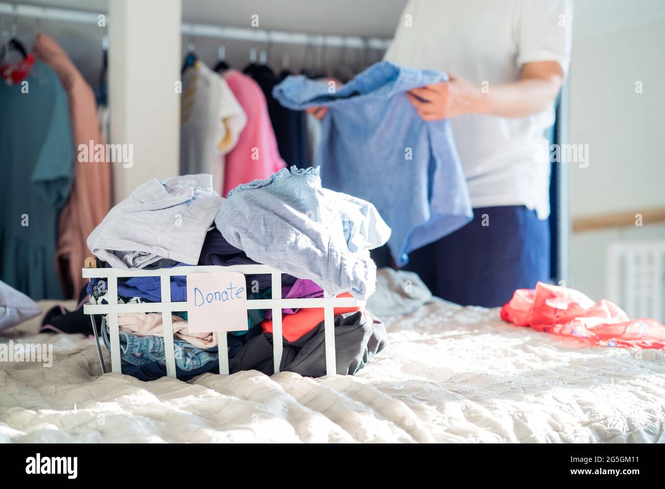 A Woman selecting clothes from her wardrobe for donating to a Charity shop. Decluttering Clothes