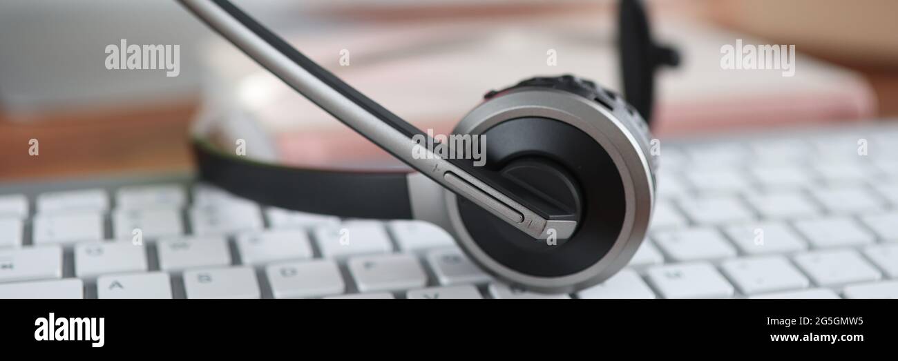Black headset lying on computer keyboard closeup Stock Photo