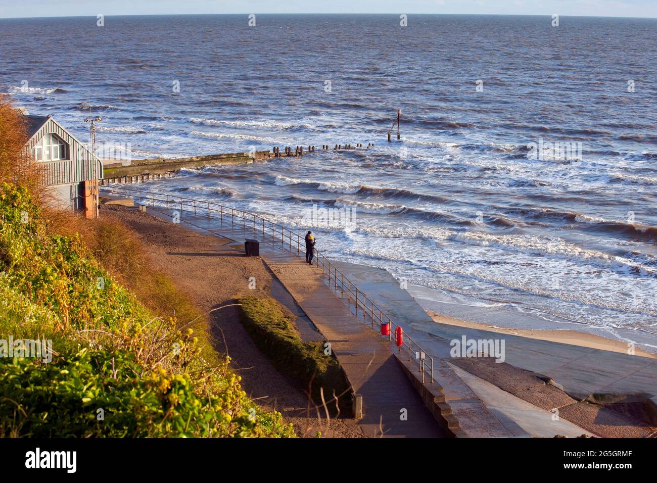 A couple look out to sea next to the lifeboat station at Mundesley on the North Norfolk coast, England. image taken April 2021 Stock Photo