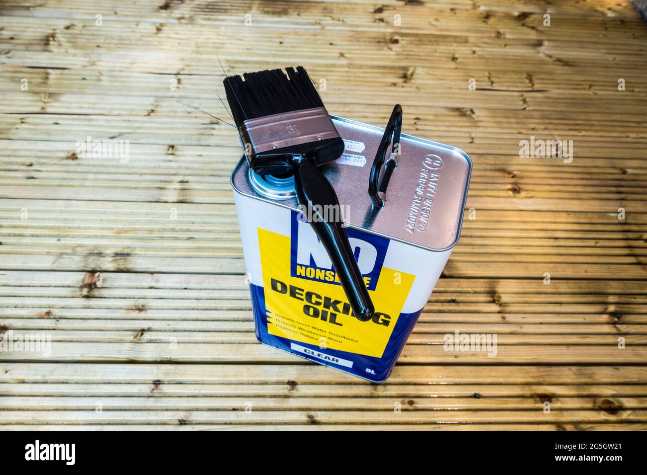 Decking oil in tin can with painting brush on Patio as Summer activity