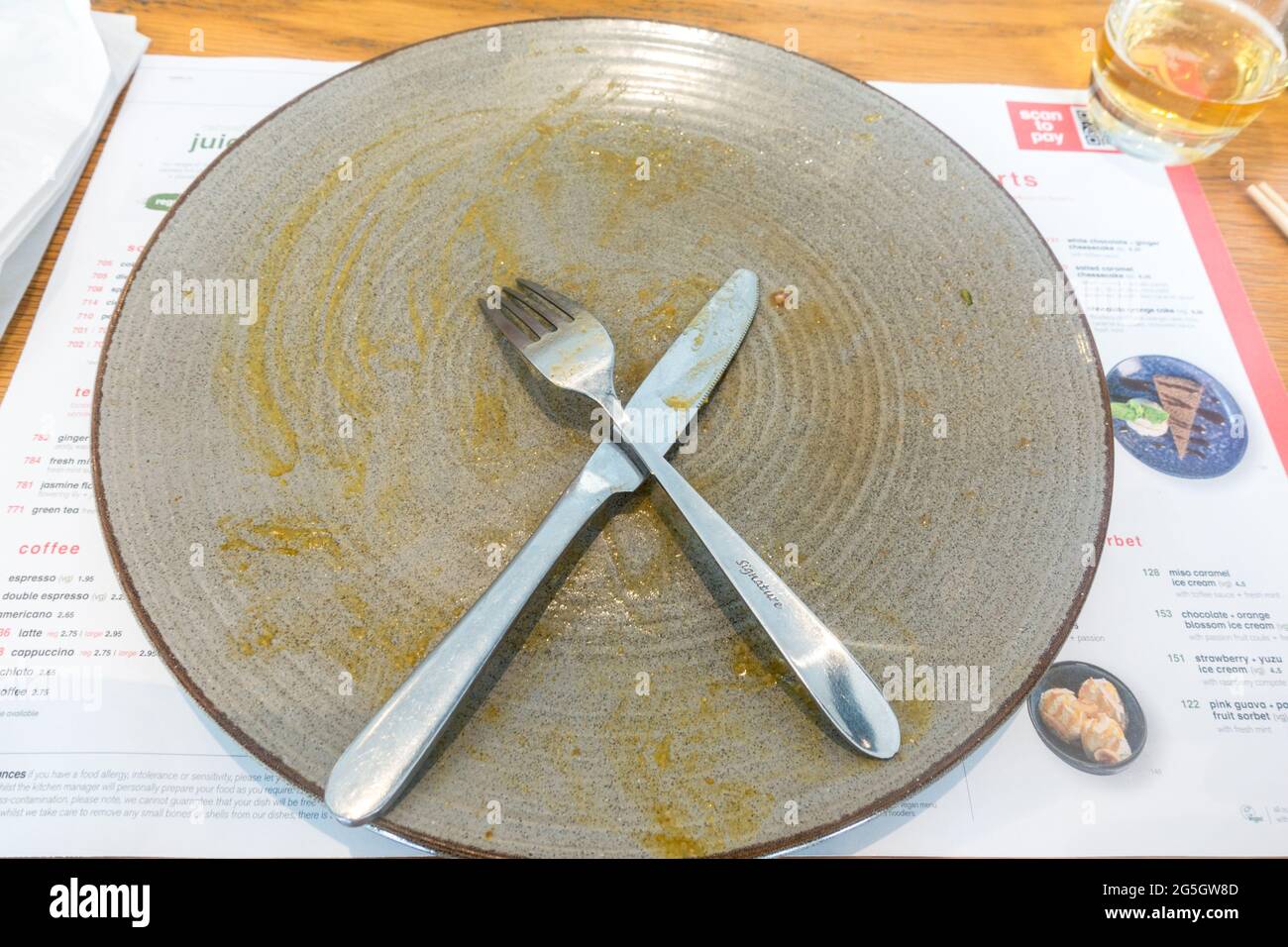 Finished meal empty plate with fork and knife Stock Photo