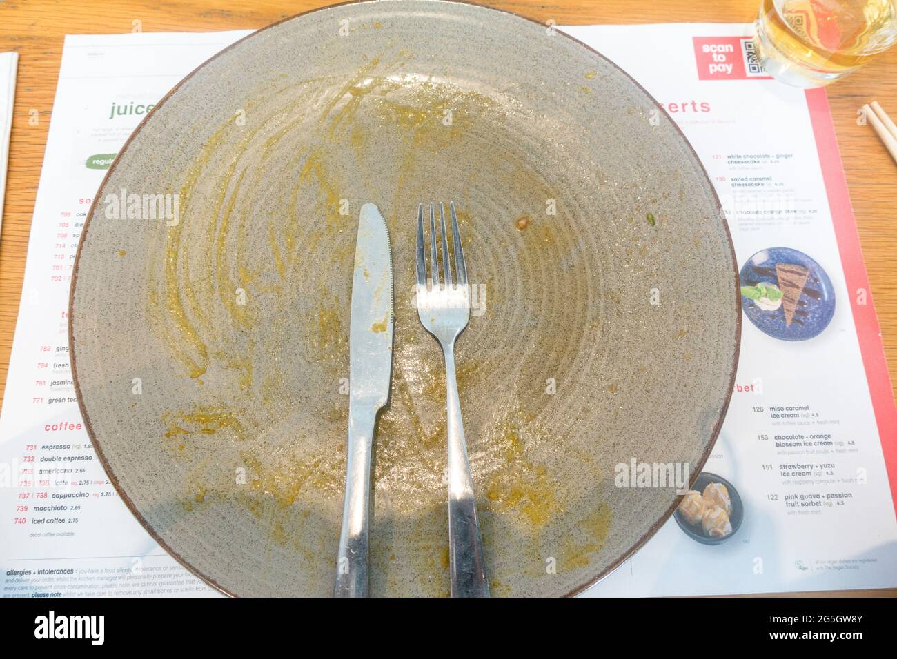 Finished meal empty plate with fork and knife Stock Photo