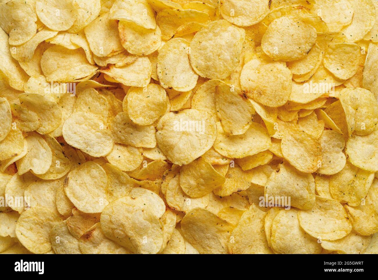 Texture of crispy potato chips. Delicious potato chips with dill background. Popular snack of