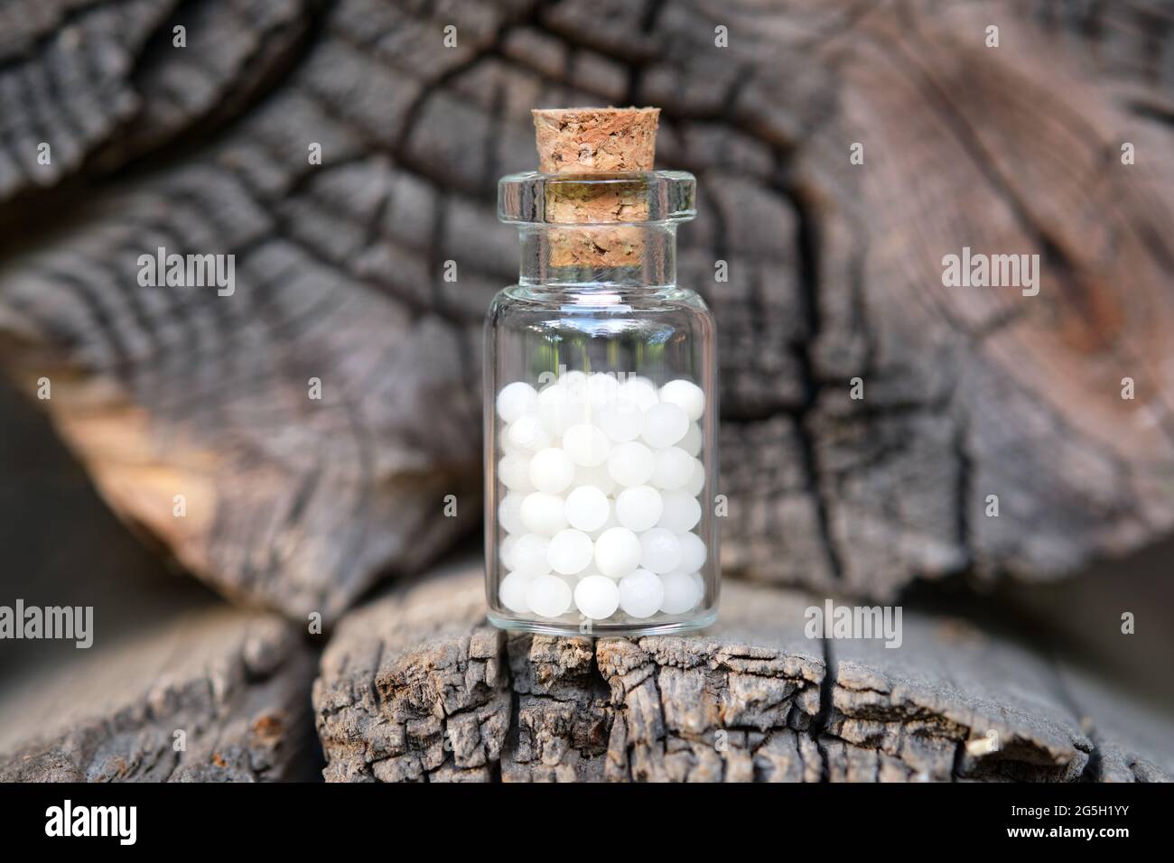 Bottle of homeopathic globules on wooden background. Homeopathy medicine concept. Stock Photo