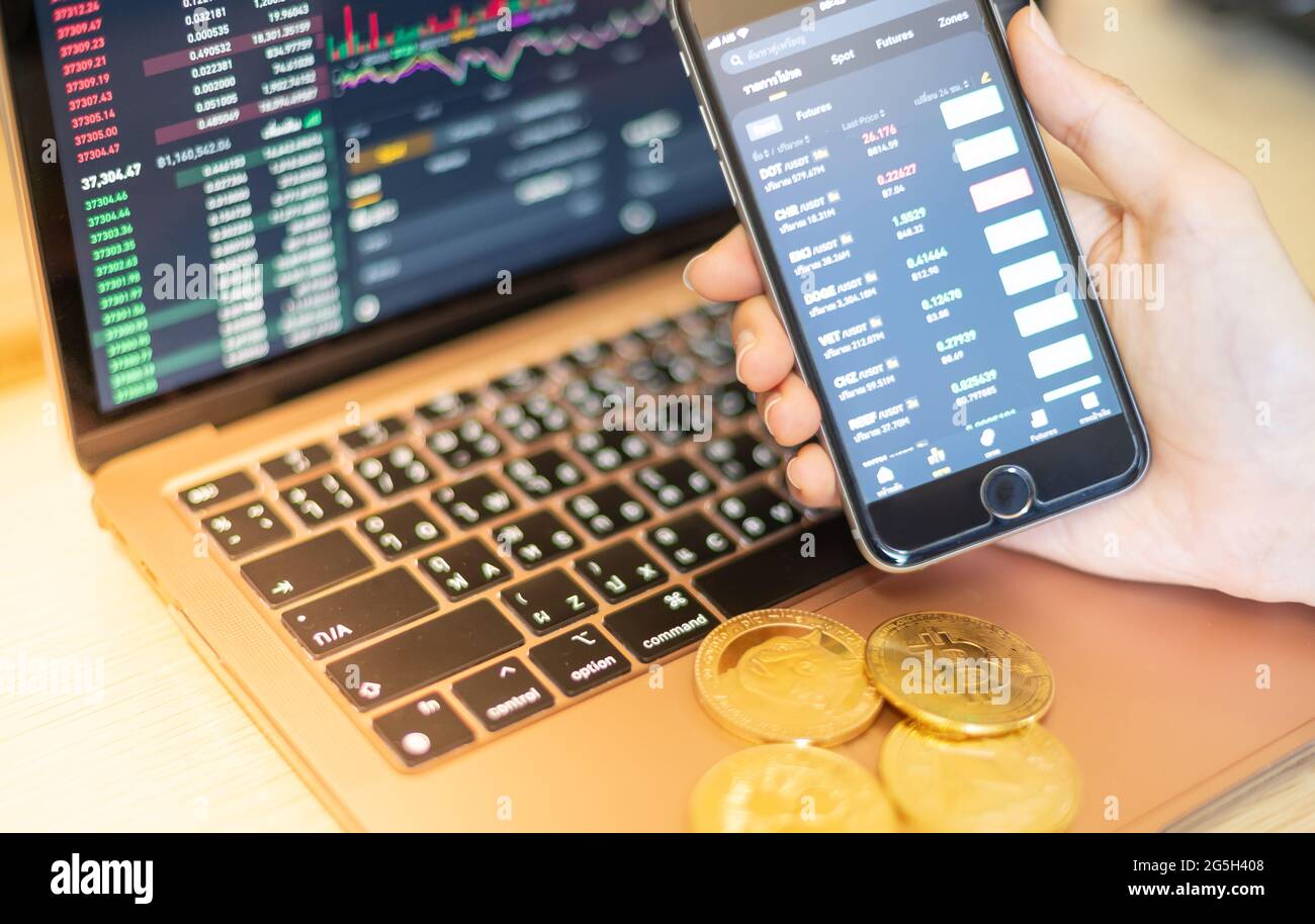 The business holding the smartphone for investor trading with the cryptocurrency  coin on the laptop with display screen and pointing Stock Photo - Alamy
