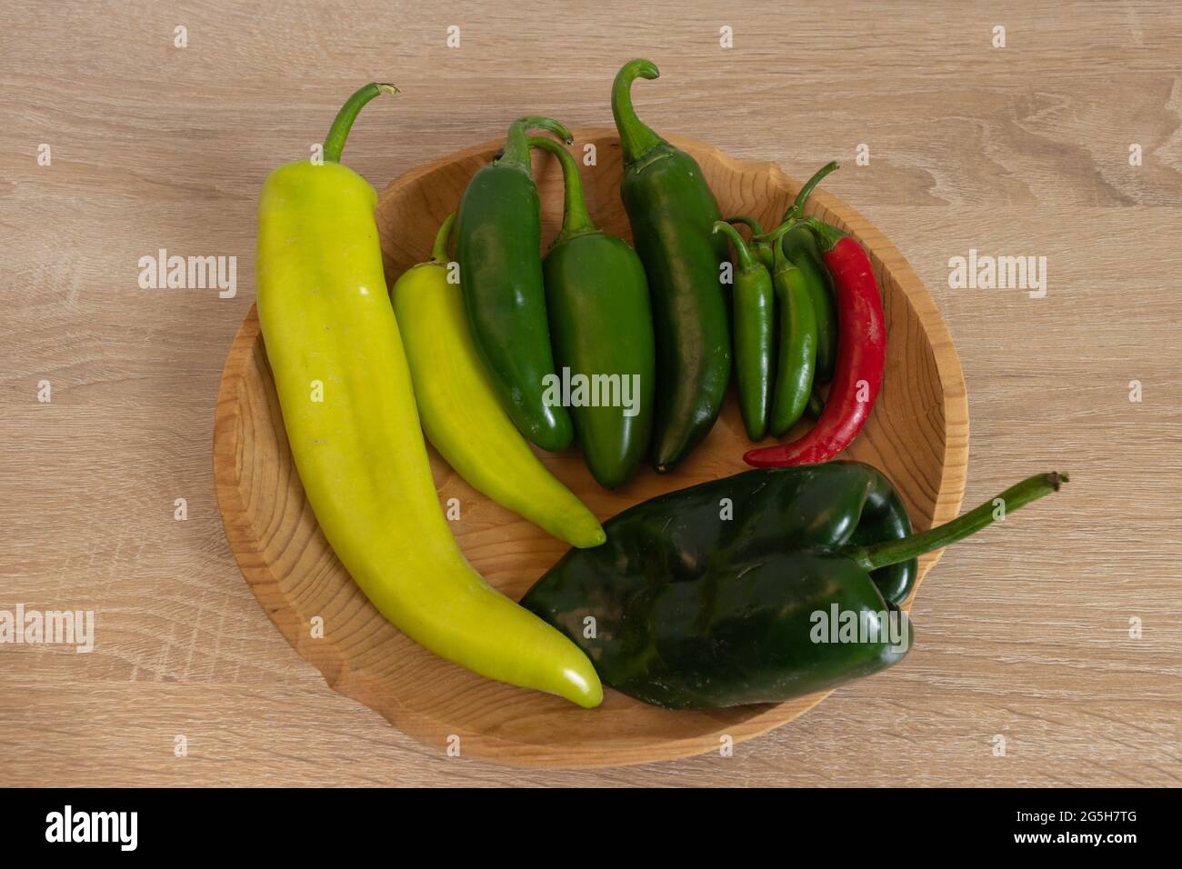 Wooden plate with mix of different peppers. Jalapeño, serrano, poblano, xcatik. Chiles frescos Stock Photo