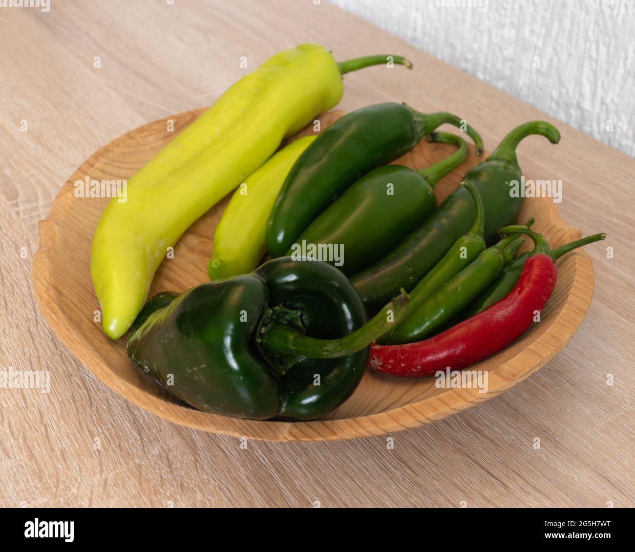 Wooden plate with mix of different peppers. Jalapeño, serrano, poblano, xcatik. Chiles frescos Stock Photo