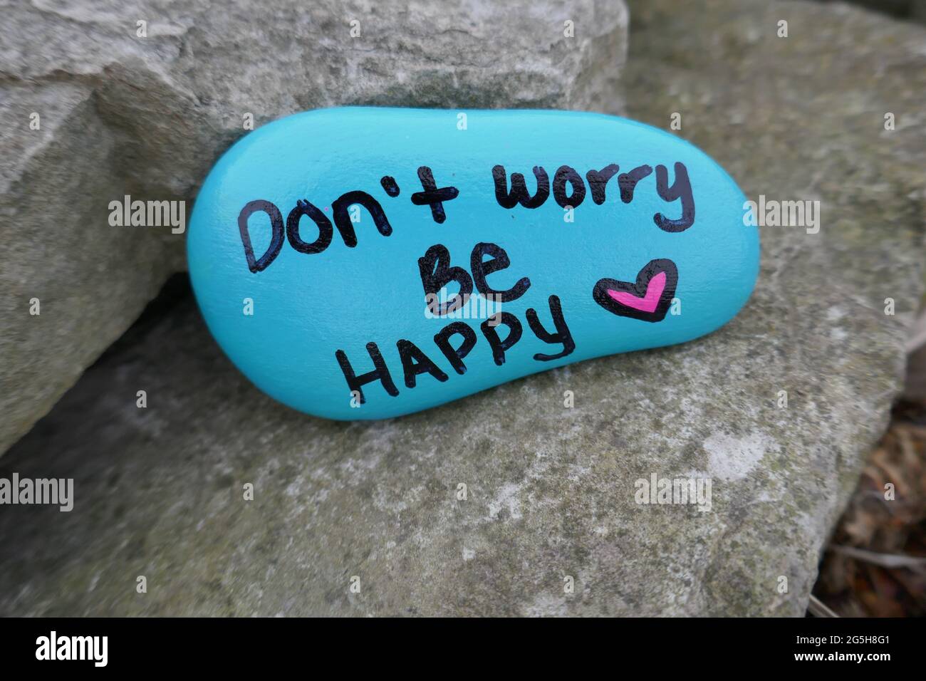 Don't worry be happy and valentine heart painted on kindness rock Stock Photo